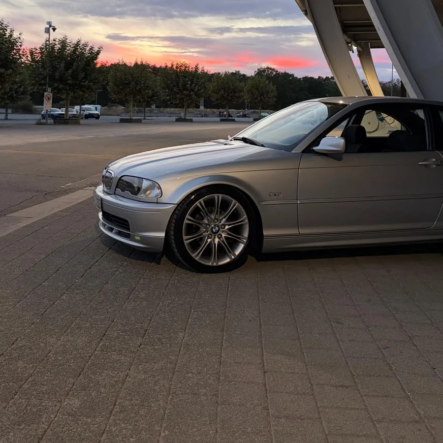 Silberner BMW an einer Stadionfassade